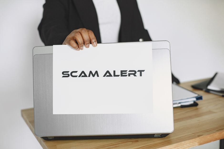 شخص يرفع لافتة تحذير فوق جهاز لابتوب للتنبيه من روابط مشبوهة